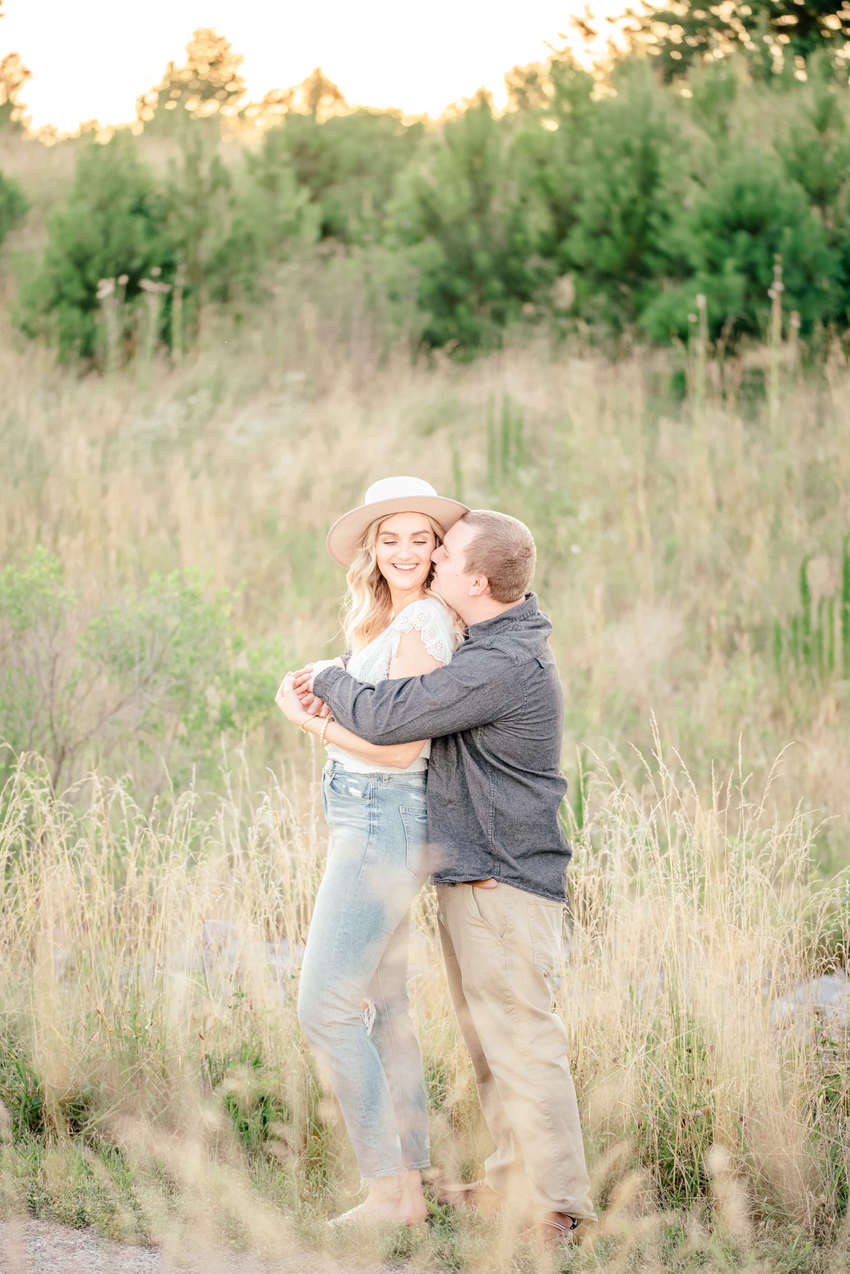 picture of man holding woman with her back to his chest, they are embracing with a warm smile as he kisses her on her cheek taken by Emily McIntyre Birmingham Alabama Wedding Photographer